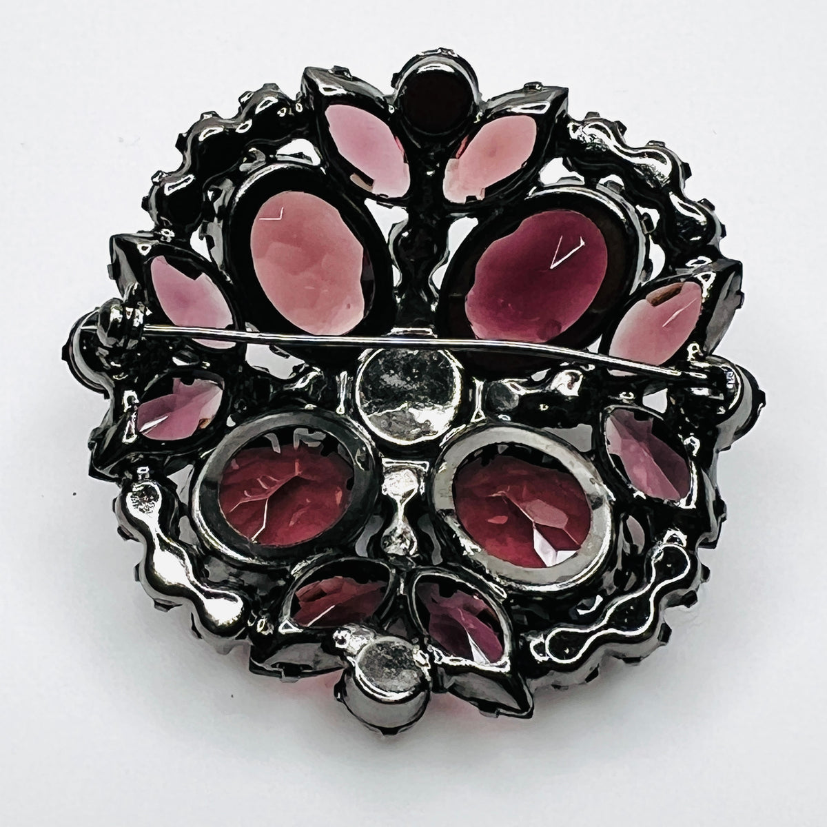 Reverse of Juliana brooch showing open-backed rhinestone settings, pooled solder construction, and pin closure.