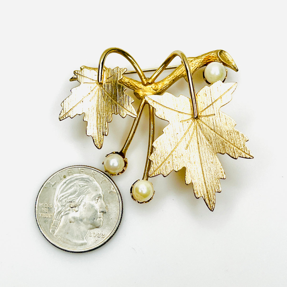 Vintage 1960s Sarah Coventry maple leaf pearl brooch beside quarter for size comparison