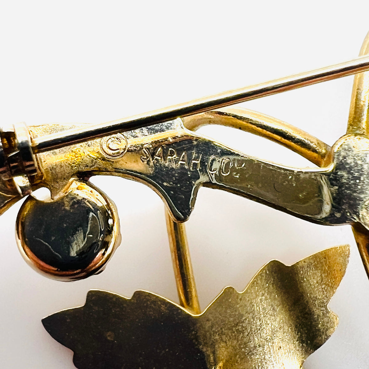 Close-up of Sarah Coventry maker signature and copyright symbol on vintage gold tone brooch