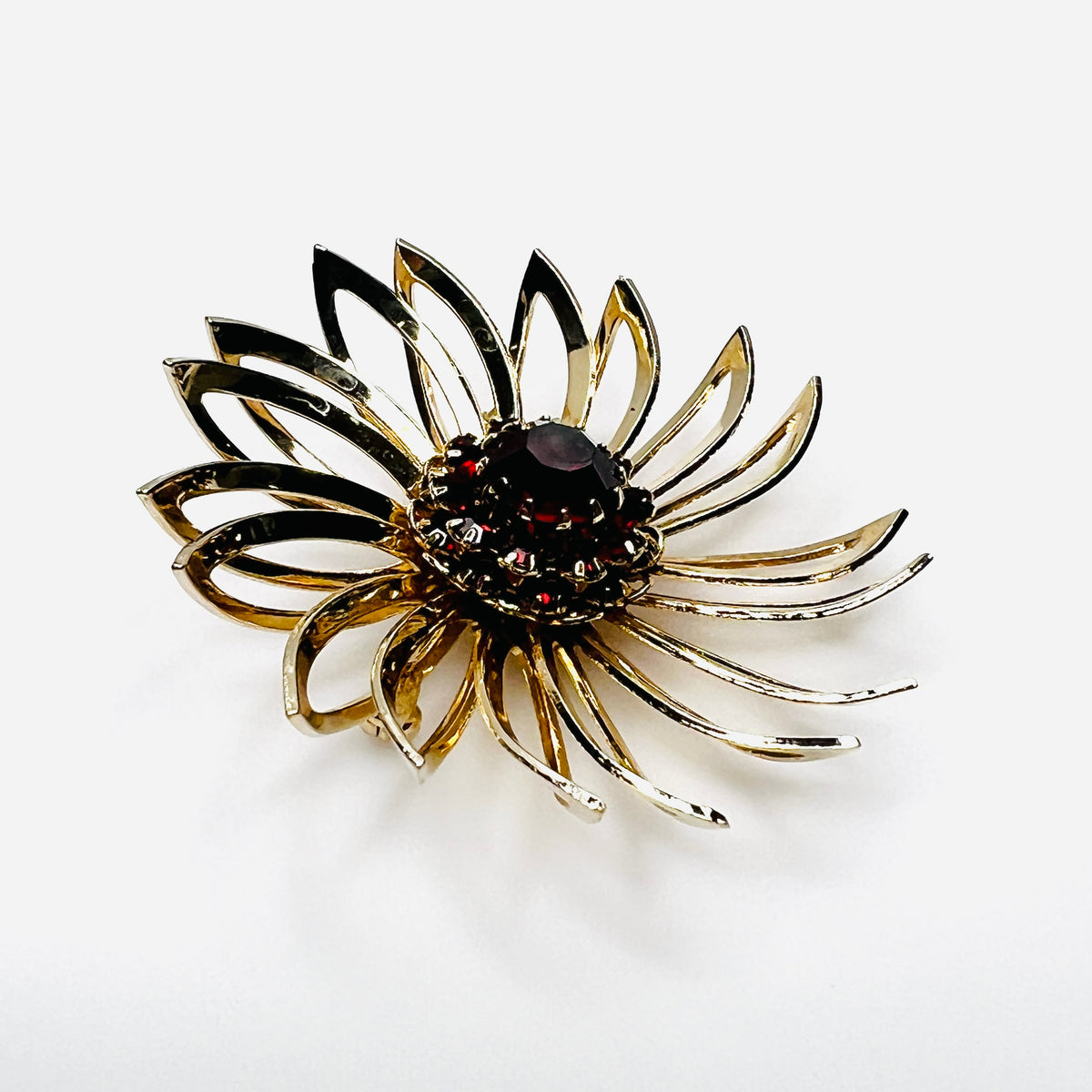 Side view of 1960s gold-tone flower brooch showing raised prong-set red rhinestones
