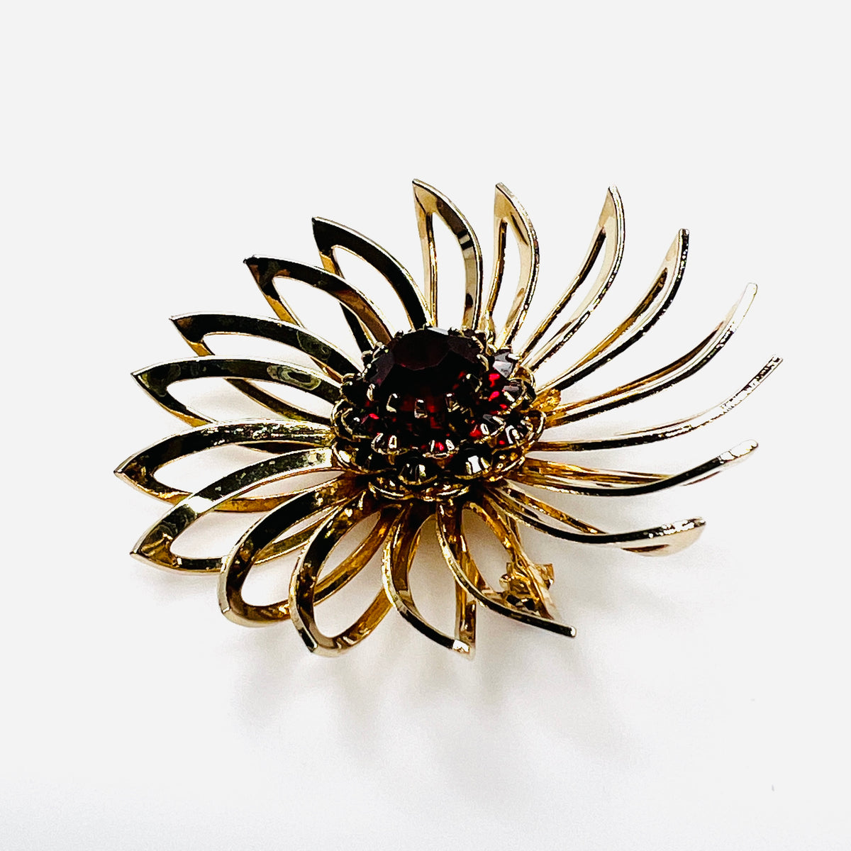 Side view of 1960s gold-tone flower brooch showing raised prong-set red rhinestones