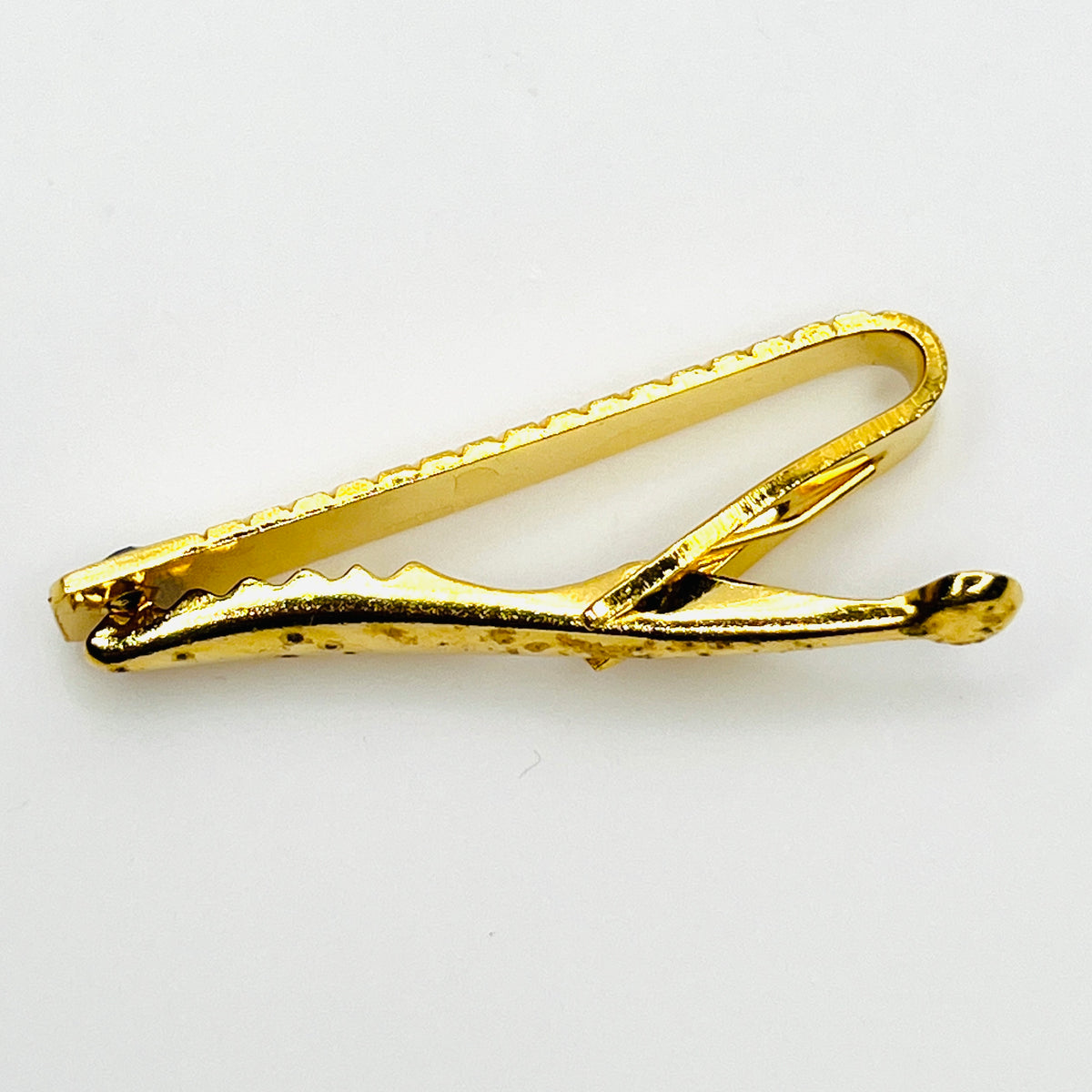 Reverse side viewe of vintage West German gold tone tie clip showing spring clip construction and wear