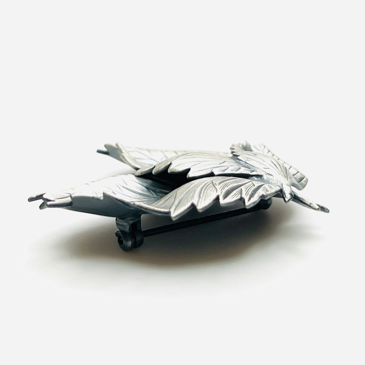 Side profile of vintage sculptural three leaf brooch in aged silver tone