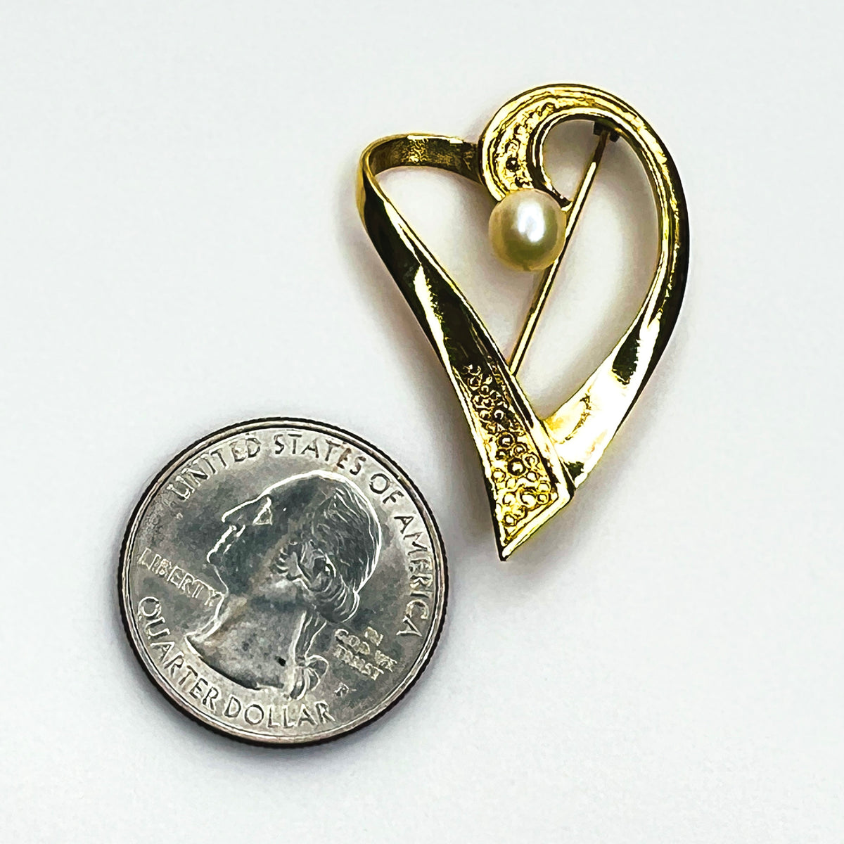 Vintage gold vermeil modernist heart brooch beside quarter showing its 1 1/2-inch height and elegant cultured pearl accent.