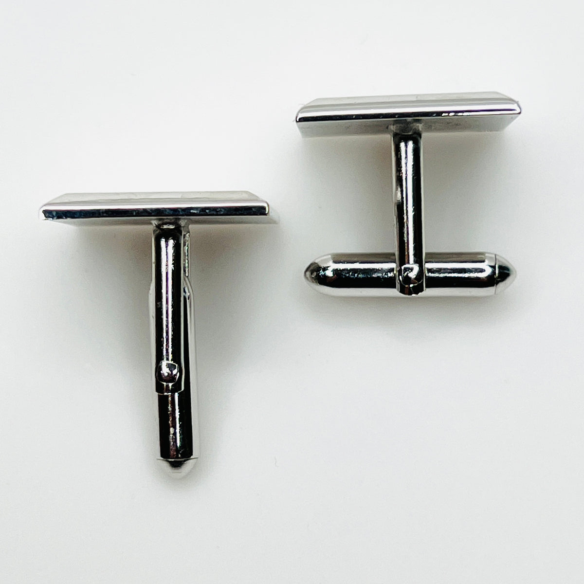 Top view of vintage Swank cufflinks showing silver tone swivel bar closures