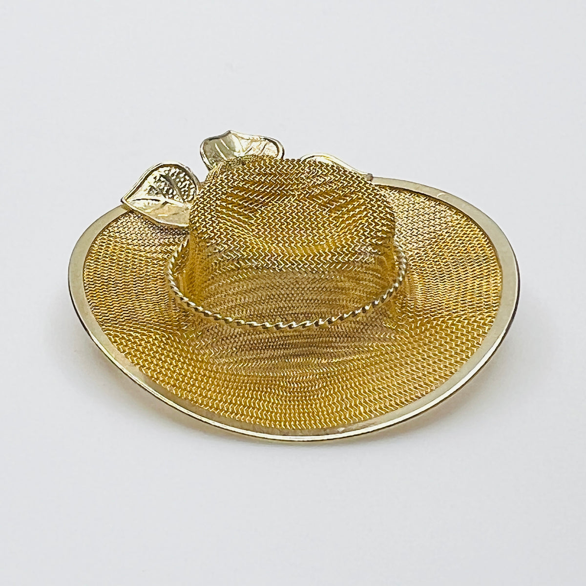 Side view of vintage gold-tone mesh hat pin showing dimensional crown, wide brim and rose embellishment