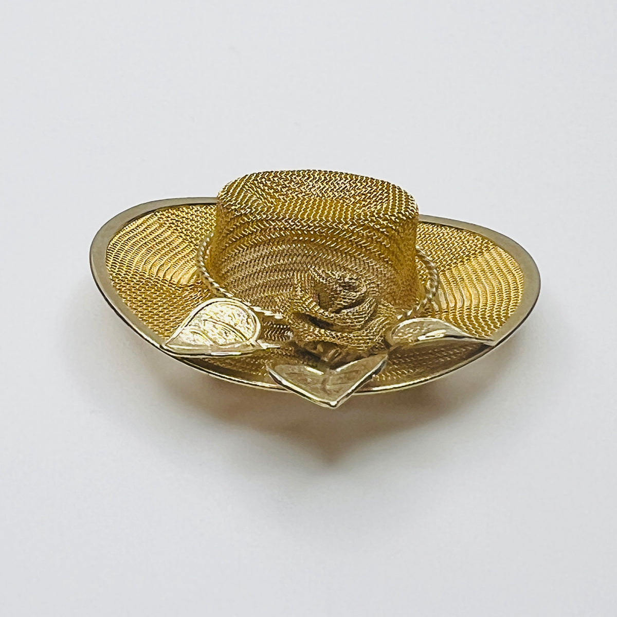 Side view of vintage gold-tone mesh hat pin showing dimensional crown, wide brim and rose embellishment