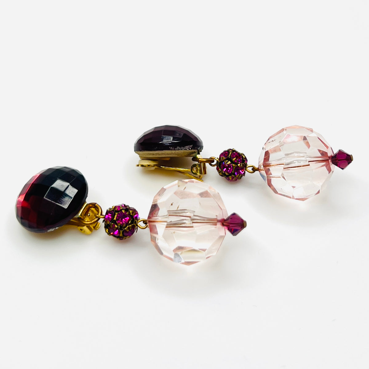 side view of vintage 1980s acrylic clip-on earrings with faceted pink beads and gold-tone hardware.