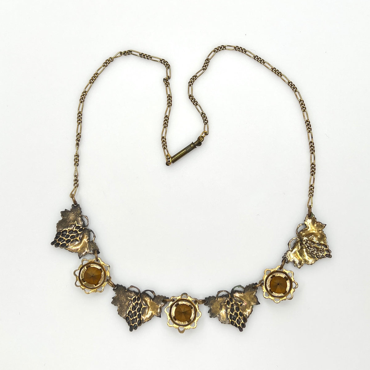 Back view of vintage enamel grape necklace with alternating rhinestone and leaf panels.