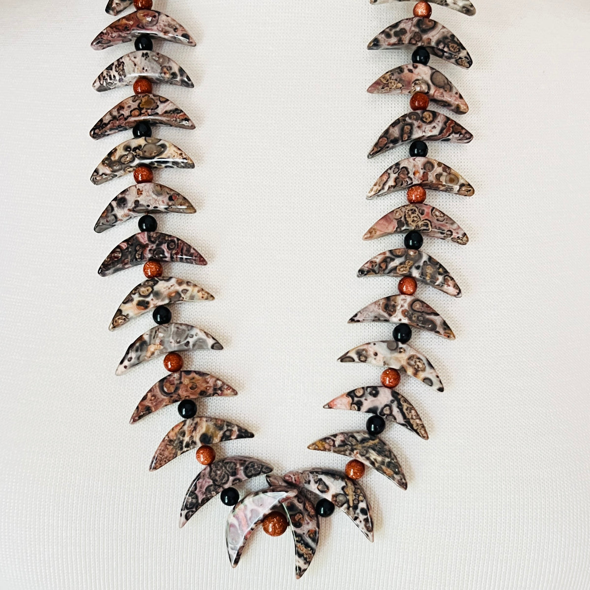 Crescent moon gemstone necklace displayed on mannequin