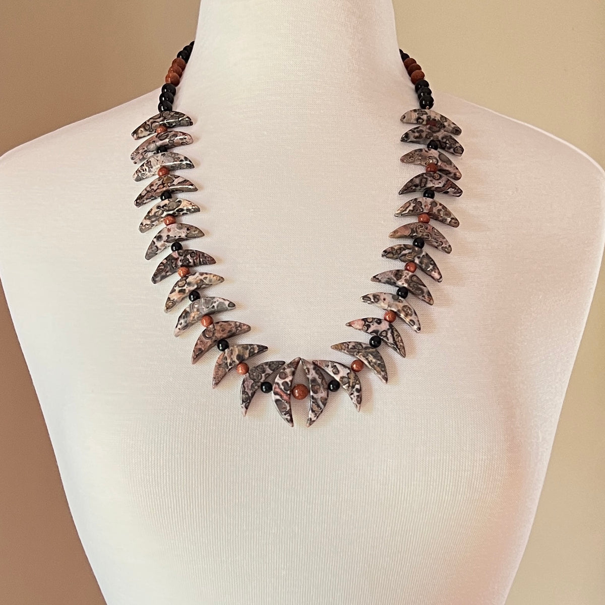 Crescent moon gemstone necklace displayed on mannequin
