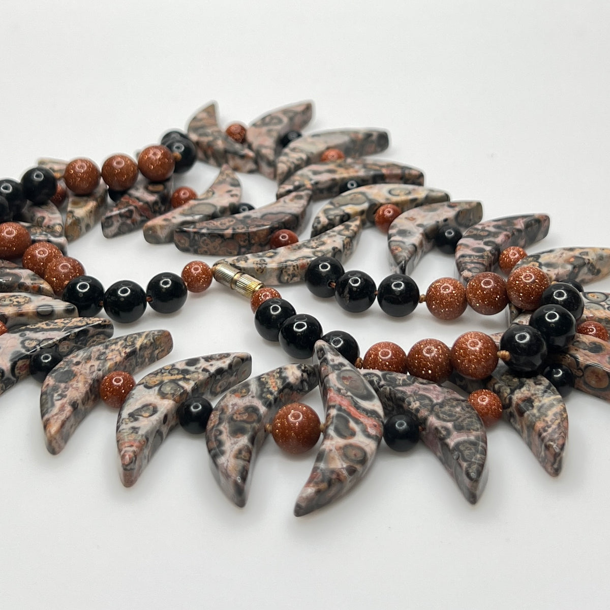 Close-up of asteroid jasper necklace with goldstone and obsidian beads