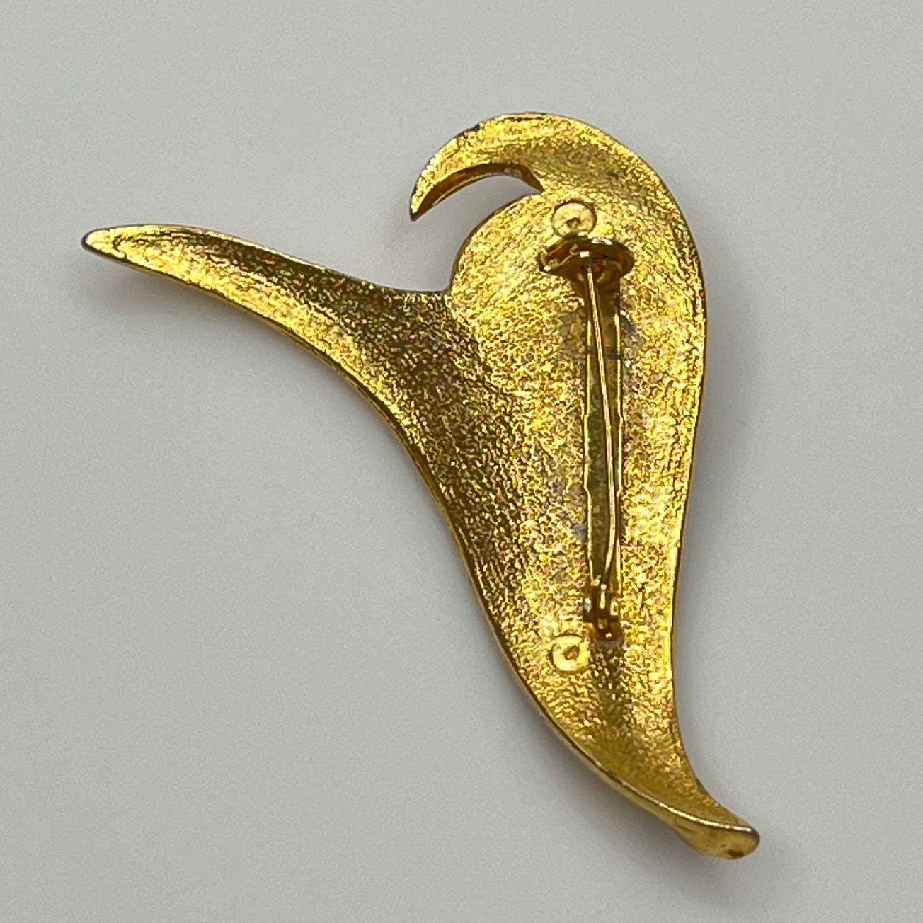 Modernist gold-tone brooch with sculptural wave shape and cobalt blue rhinestone center