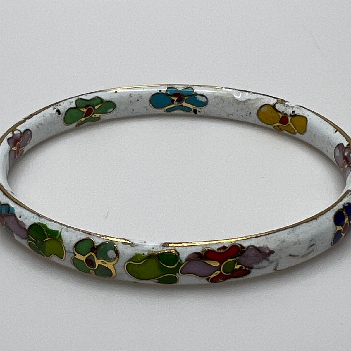 Close-up of enamel flower details on round white cloisonné bangle