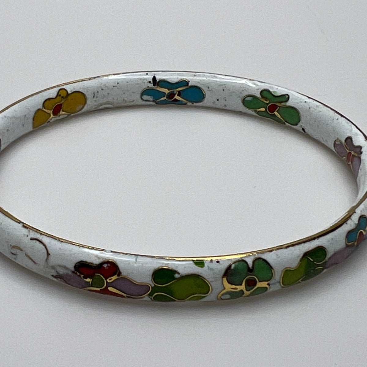 Close-up of enamel flower details on round white cloisonné bangle