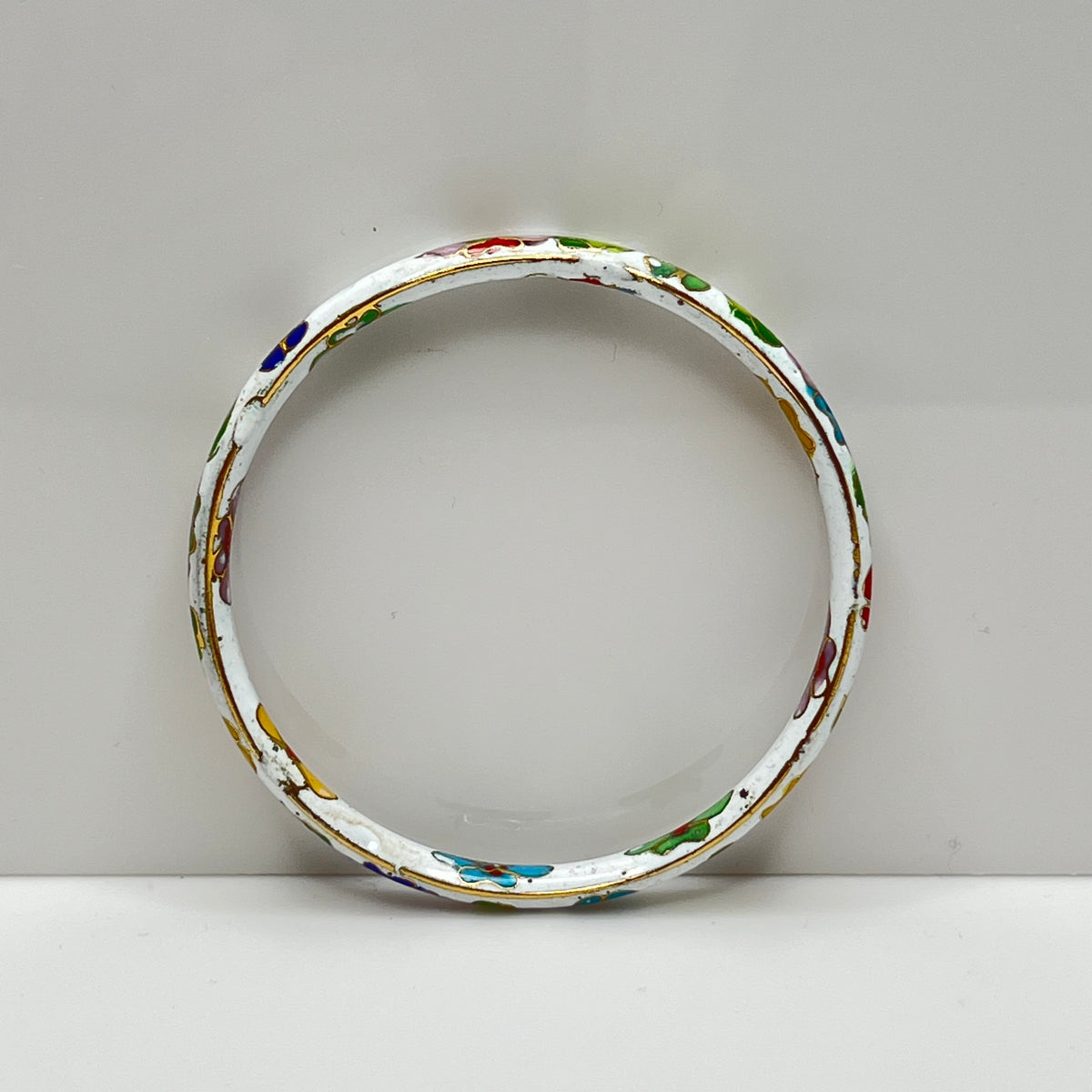 Close-up of enamel flower details on round white cloisonné bangle