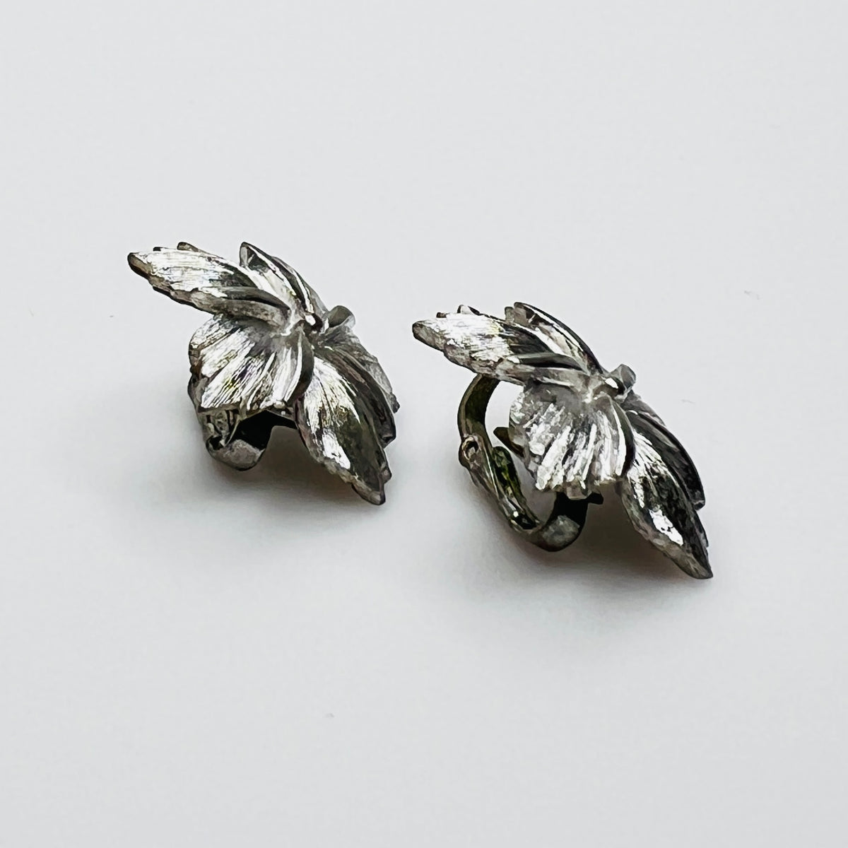 Side view of dimensional silver flower clip earrings