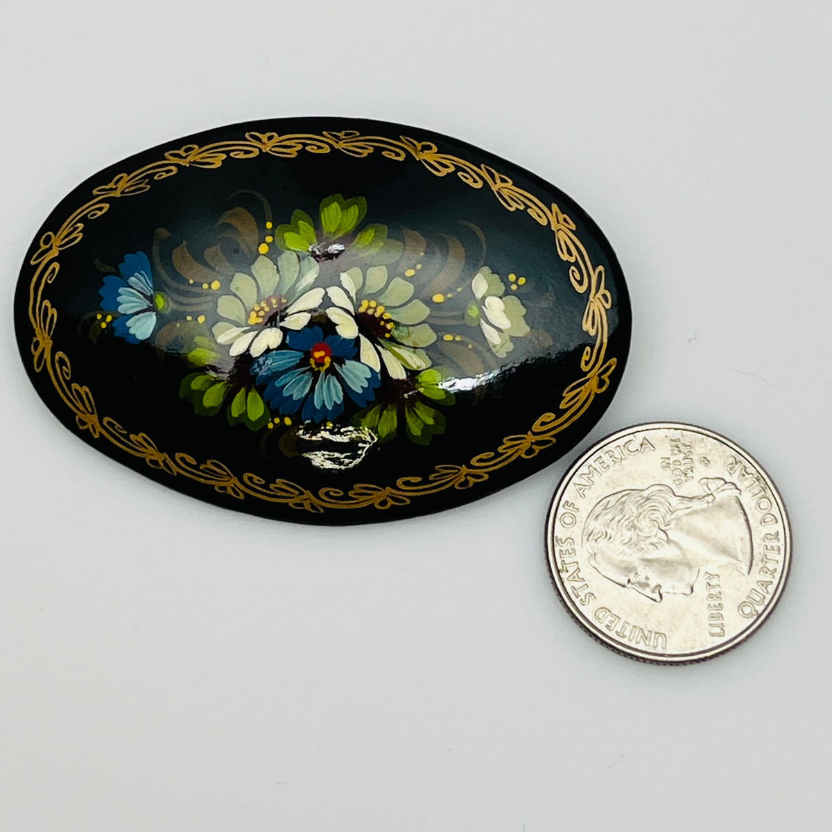 Russian black lacquer brooch with hand-painted floral design and gold border