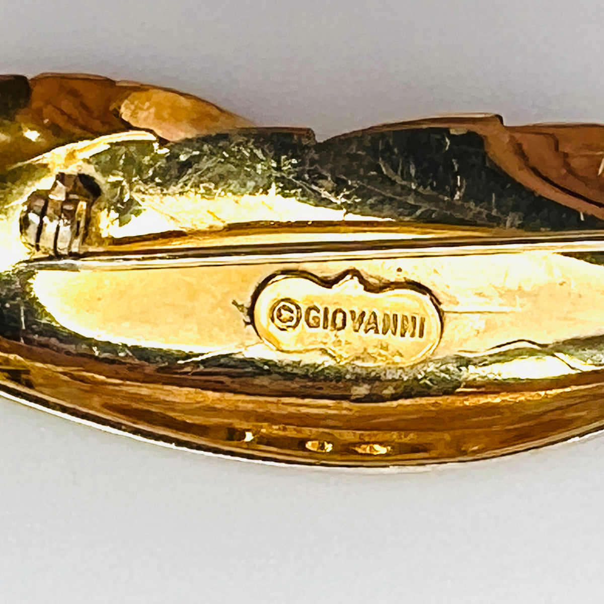 Close-up of signed Giovanni maker's mark on vintage gold tone leaf brooch