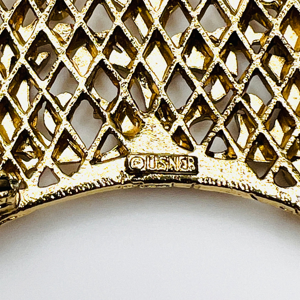 Close-up of Lisner maker's signature and copyright symbol on reverse of vintage gold-tone crescent brooch.