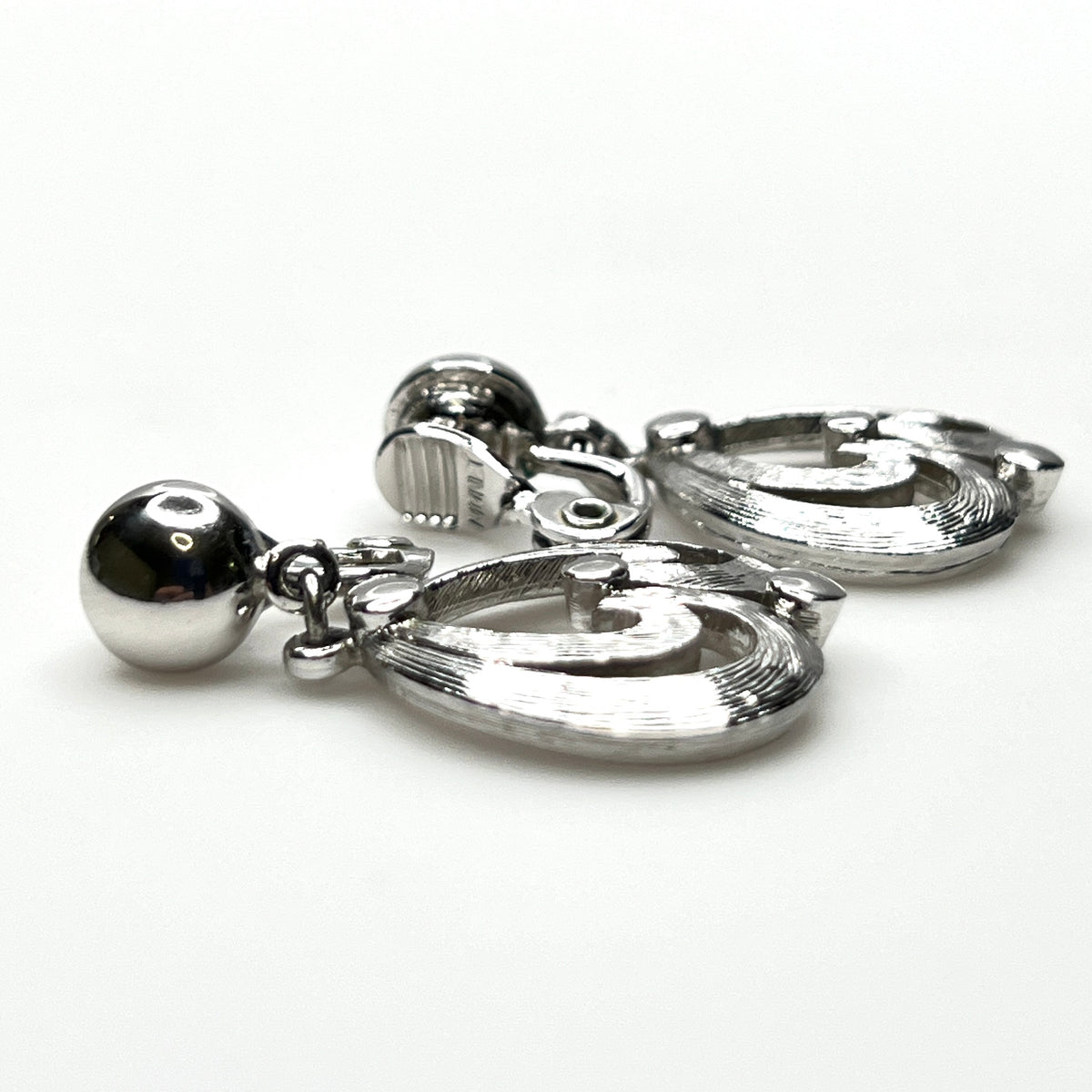 Side view of vintage Monet silver tone articulated clip-on earrings