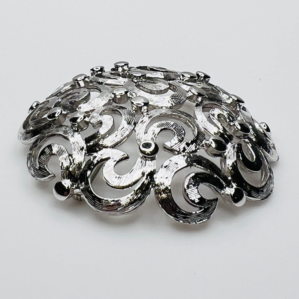 Side View of textured swirl filigree silver tone brooch