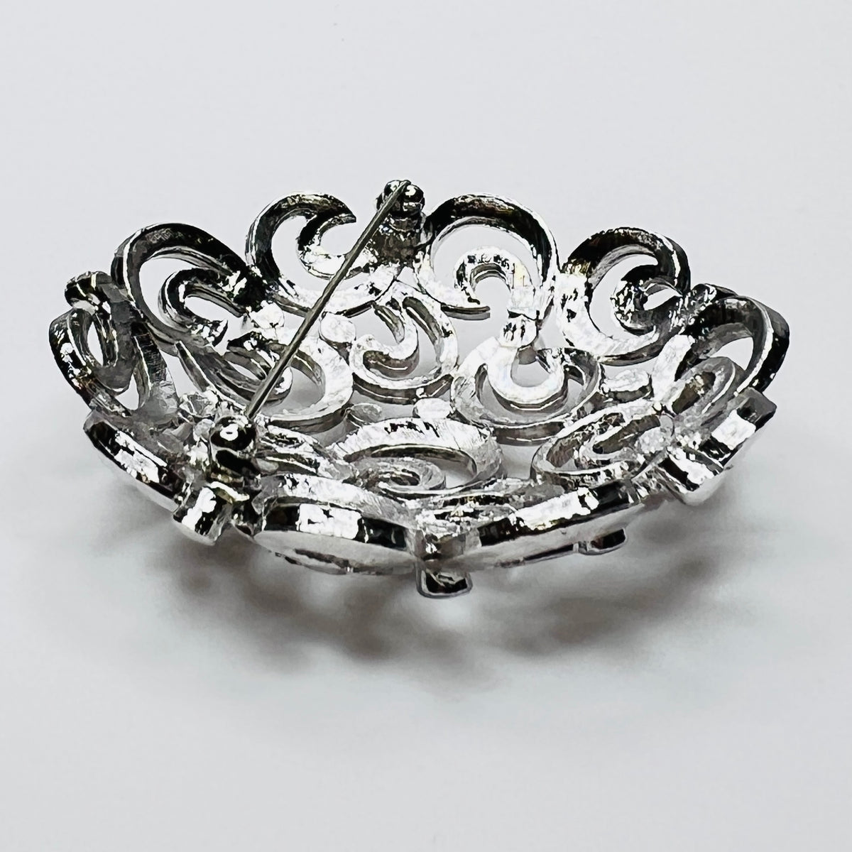 Close-up of textured swirl filigree silver tone brooch