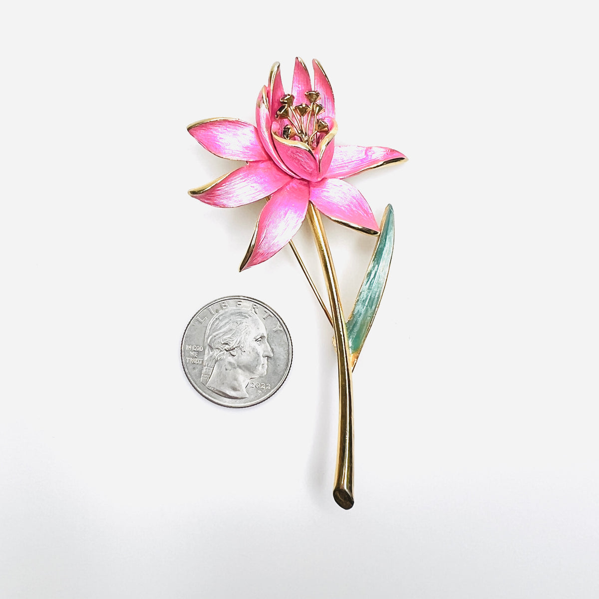 Park Lane pink floral brooch shown beside quarter for scale with green enamel leaf