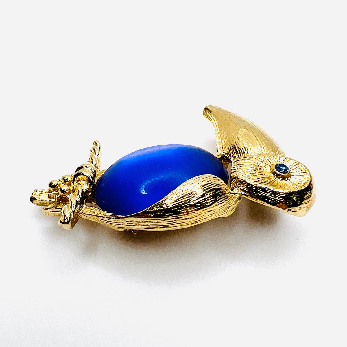 side view of gold-tone toucan brooch with luminous purple cabochon belly and rhinestone eye