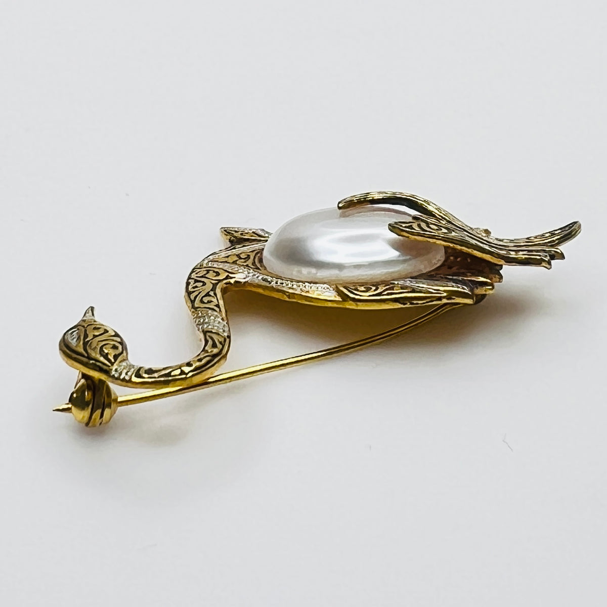 Side view of vintage swan brooch with faux pearl cabochon center