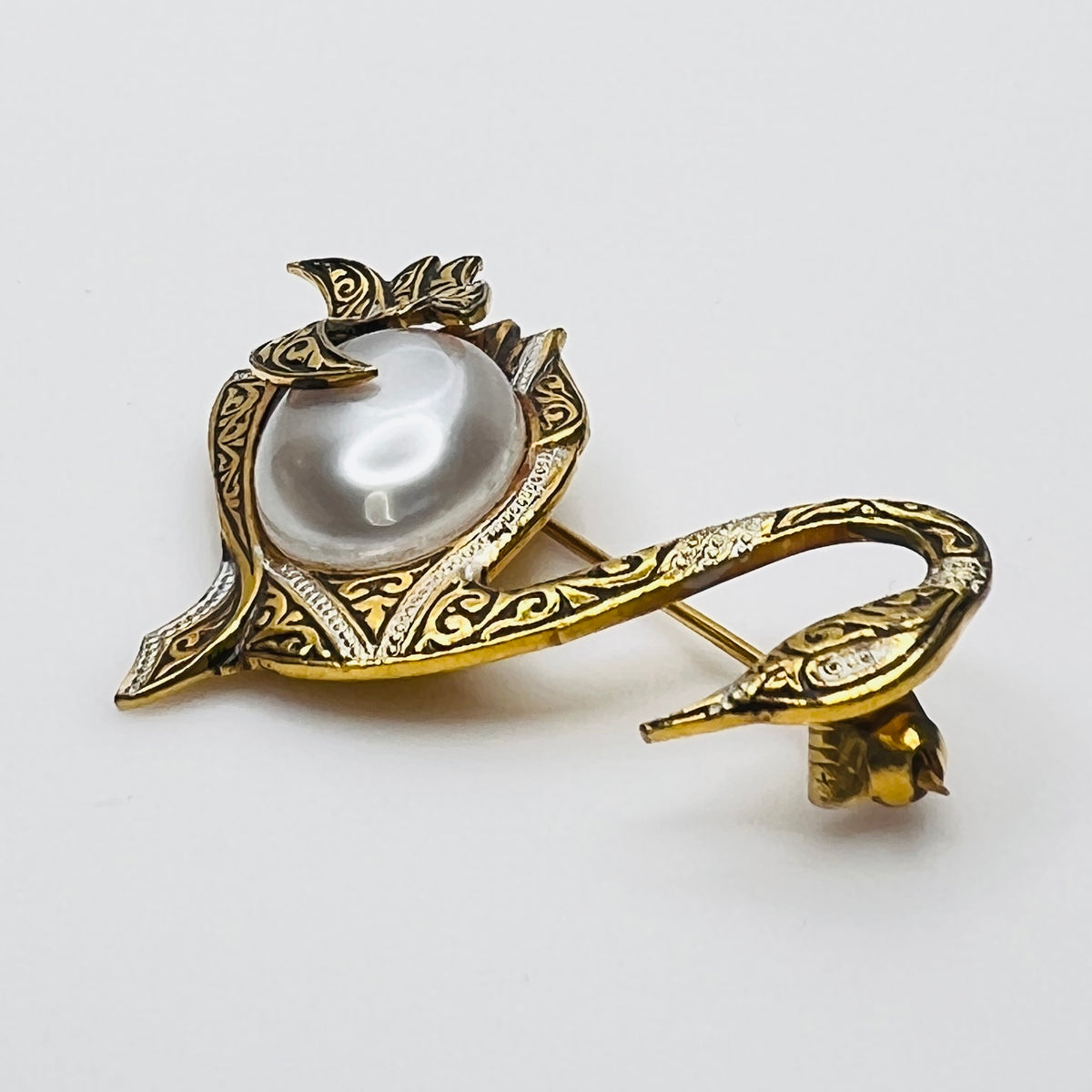 Side view of vintage swan brooch with faux pearl cabochon center