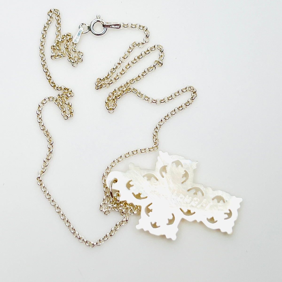 Reverse of Bethlehem Mother of Pearl cross pendant showing carved back and sterling chain.