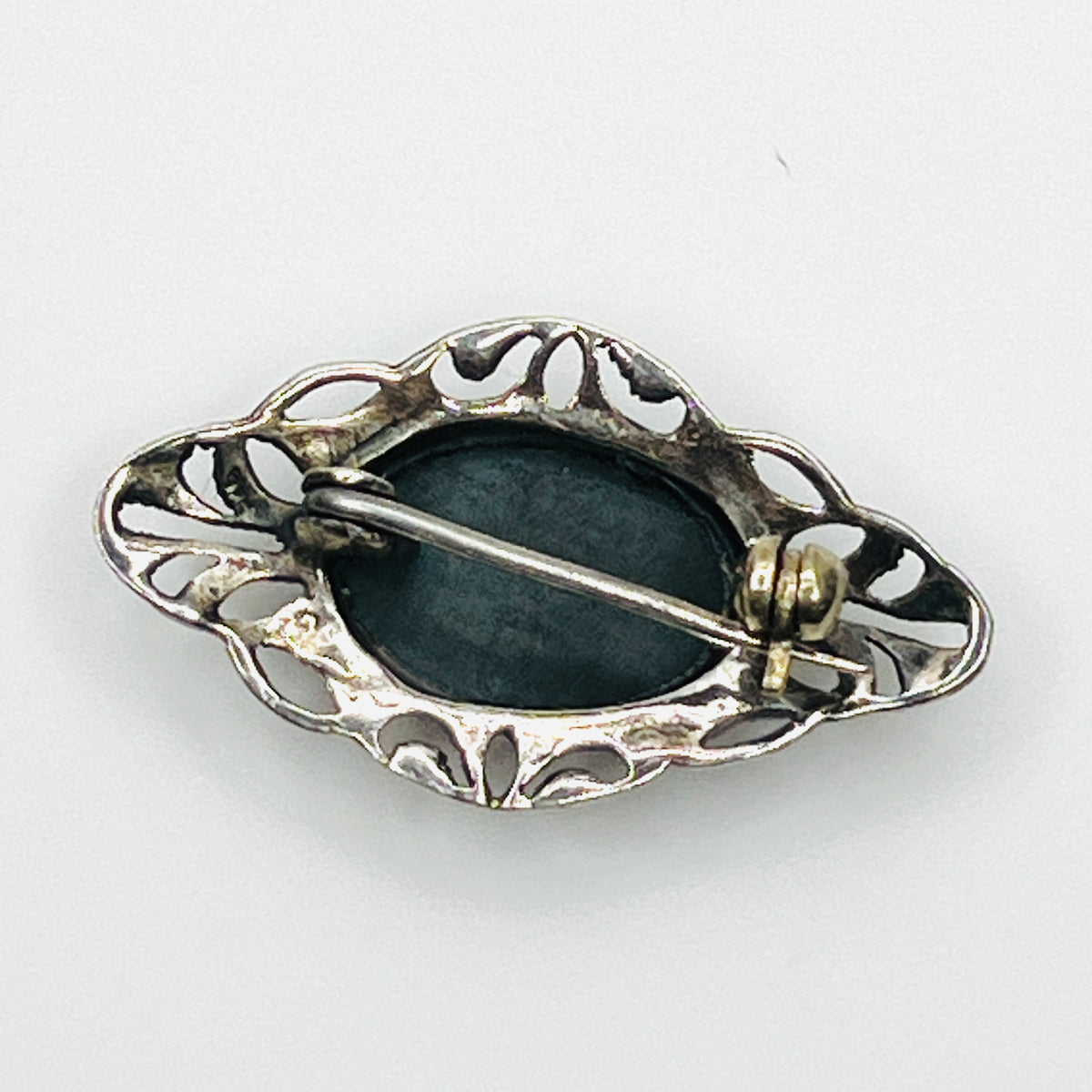 Reverse of vintage sterling silver black onyx brooch showing openwork construction and rollover pin clasp.