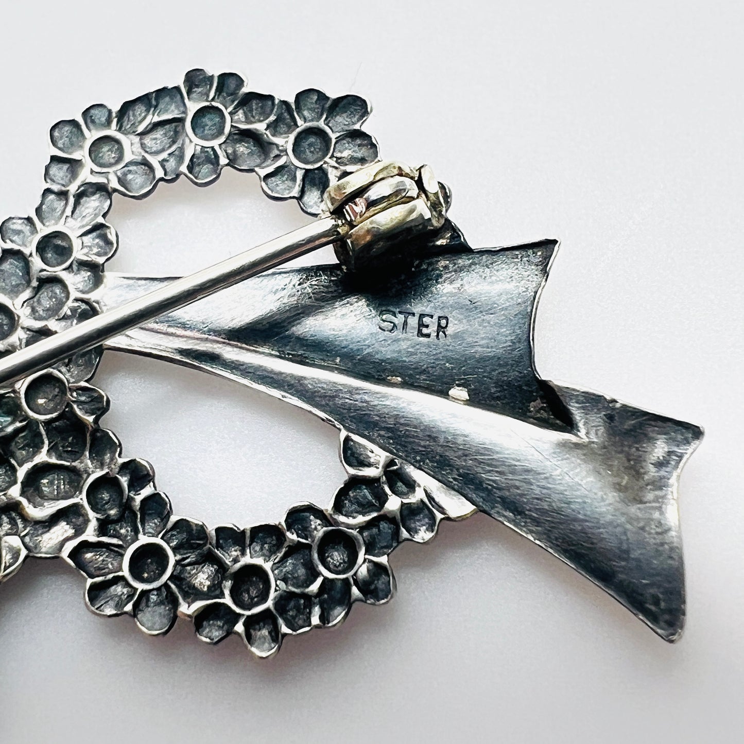 Close-up of sterling stamp on vintage sterling silver floral wreath bow brooch.