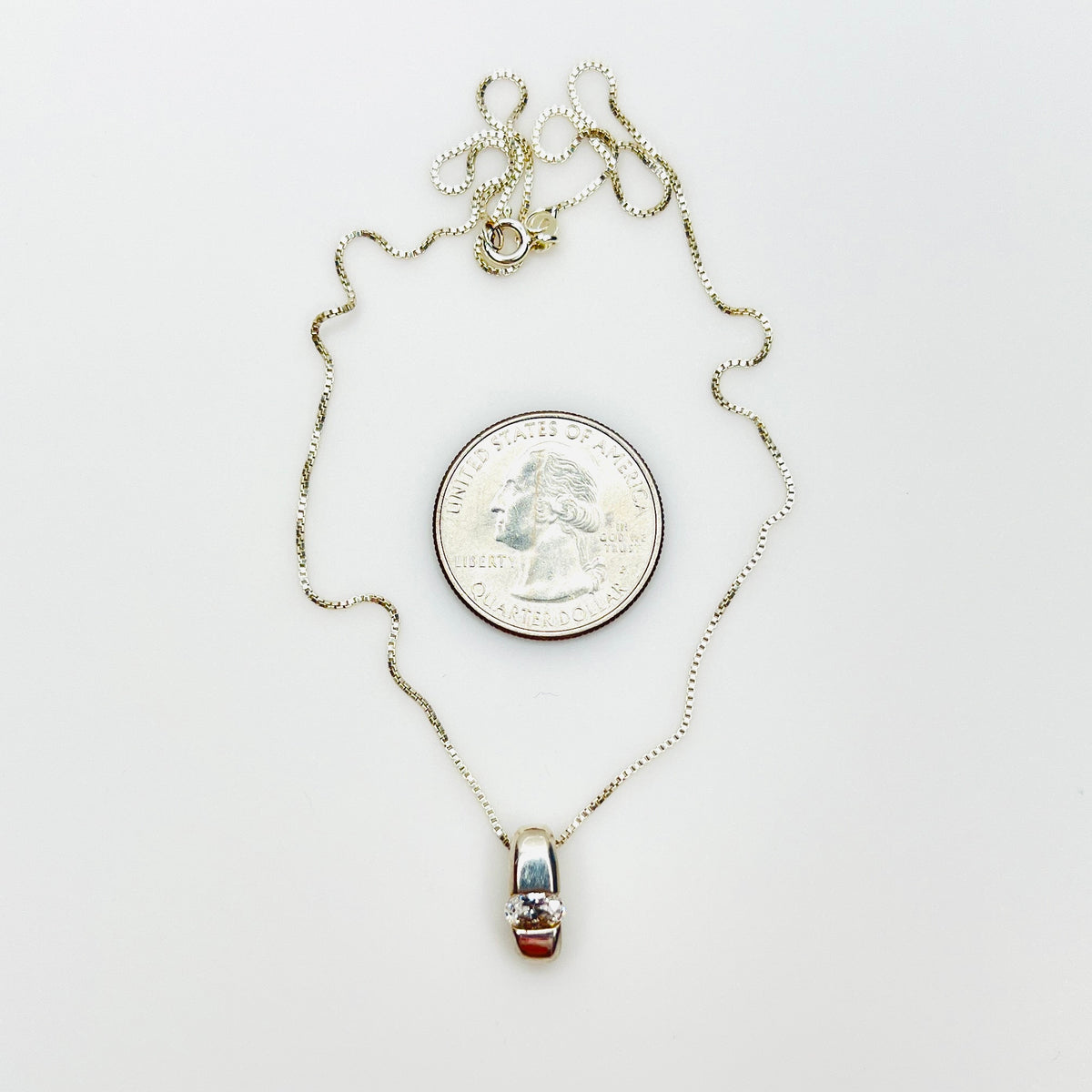 Sterling silver CZ pendant necklace beside quarter showing pendant size and 16-inch chain.