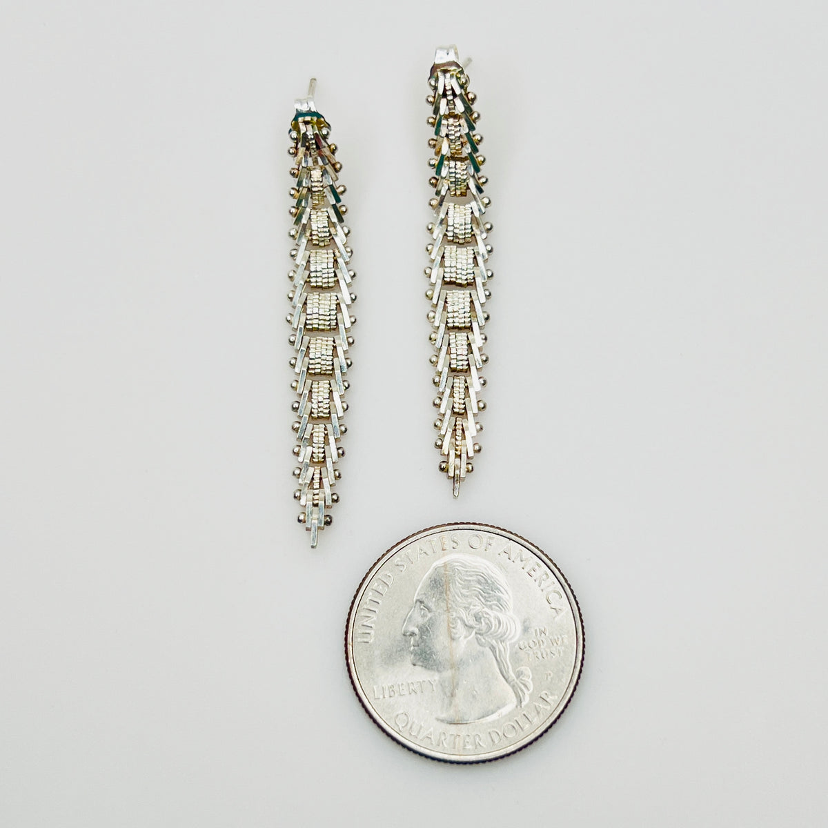 Sterling silver geometric dangle earrings beside quarter for size reference