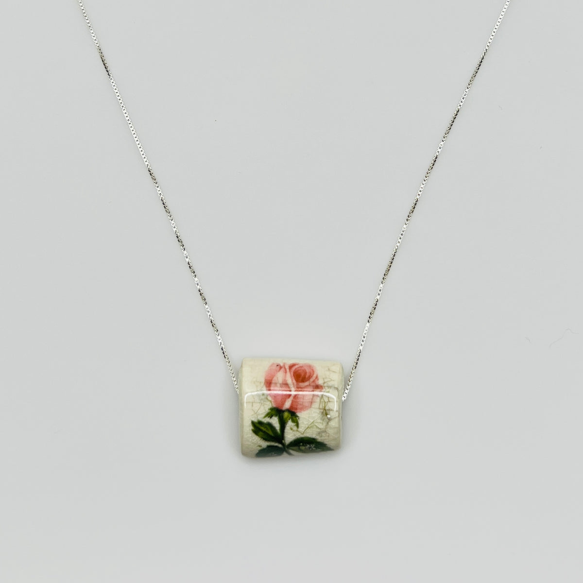 Close-up of pink rose tile pendant with crackle glaze detail