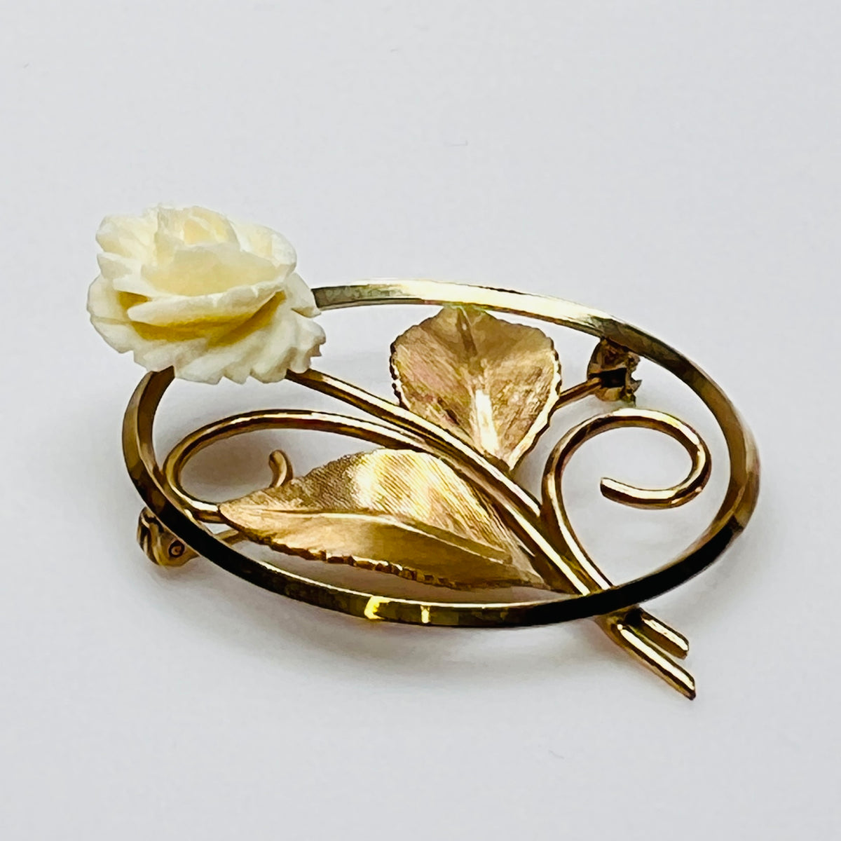 Side view of circular rose pin with gold-tone leaves