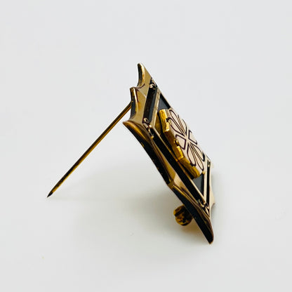 Angled view of cTo enamel brooch with raised medallion and deco-style edges