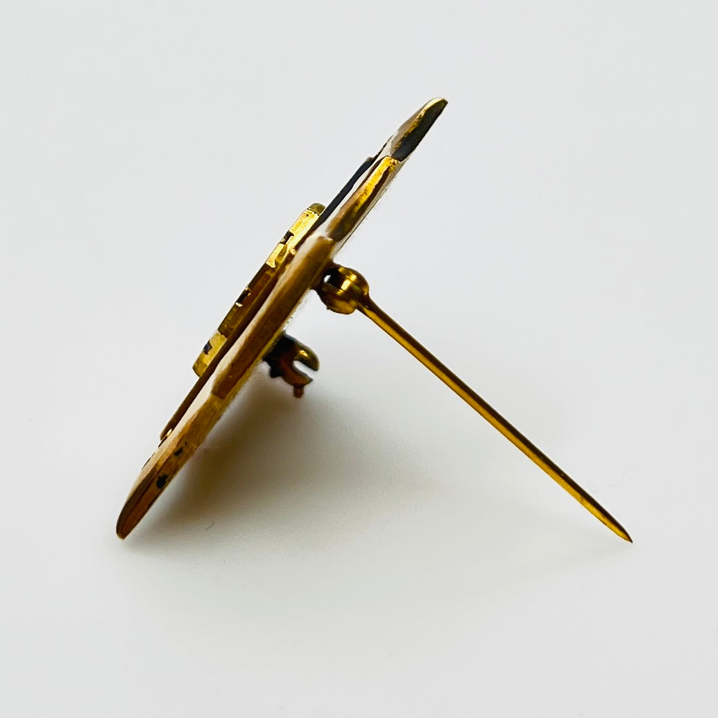 Angled view of cTo enamel brooch with raised medallion and deco-style edges