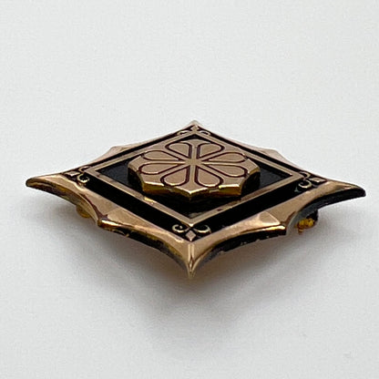 Angled view of cTo enamel brooch with raised medallion and deco-style edges