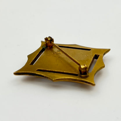 Angled view of cTo enamel brooch with raised medallion and deco-style edges