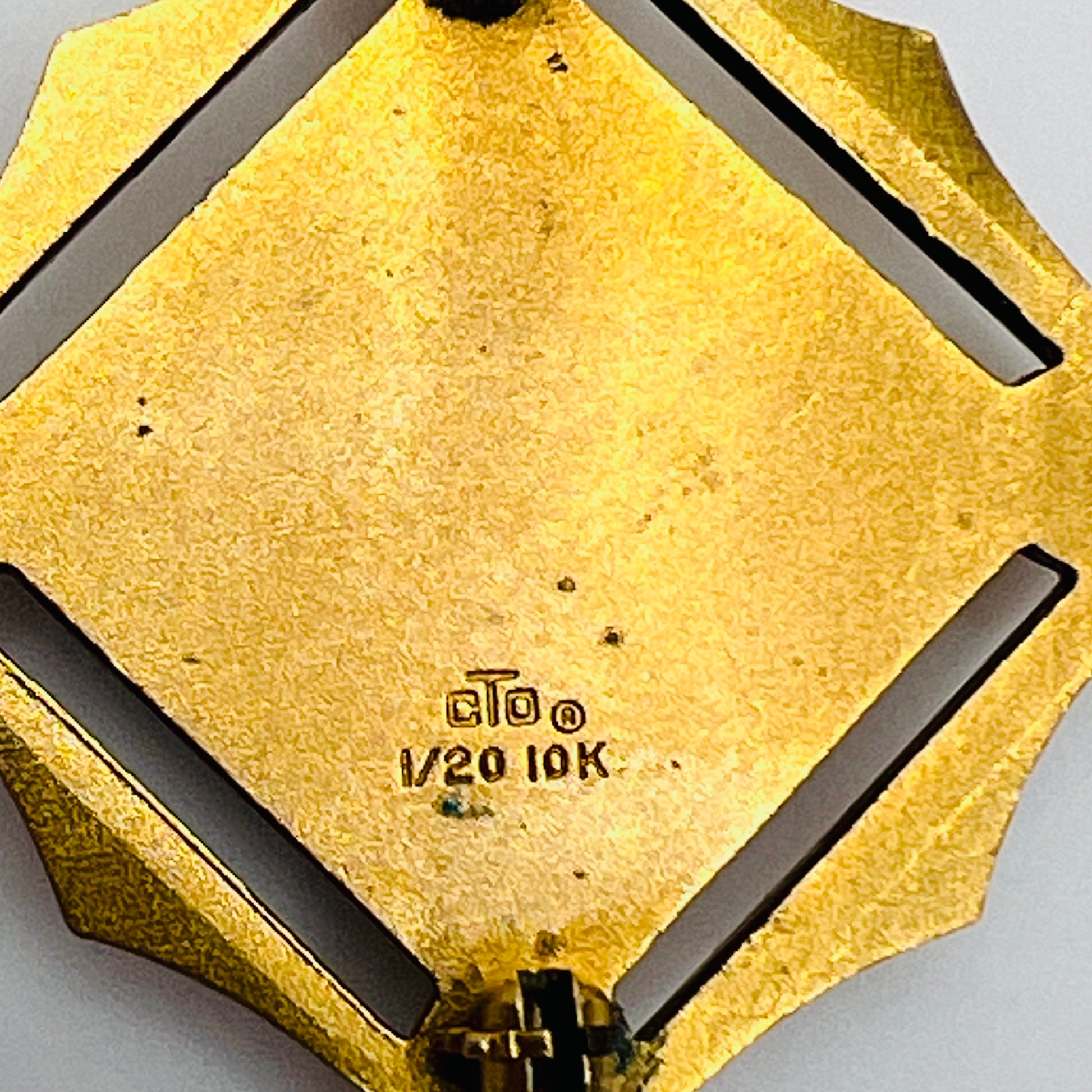 Close-up of back showing “cTo 1/20 10K” hallmark on textured gold surface