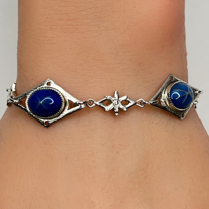 Faux star sapphire bracelet on wrist with silver-tone floral links