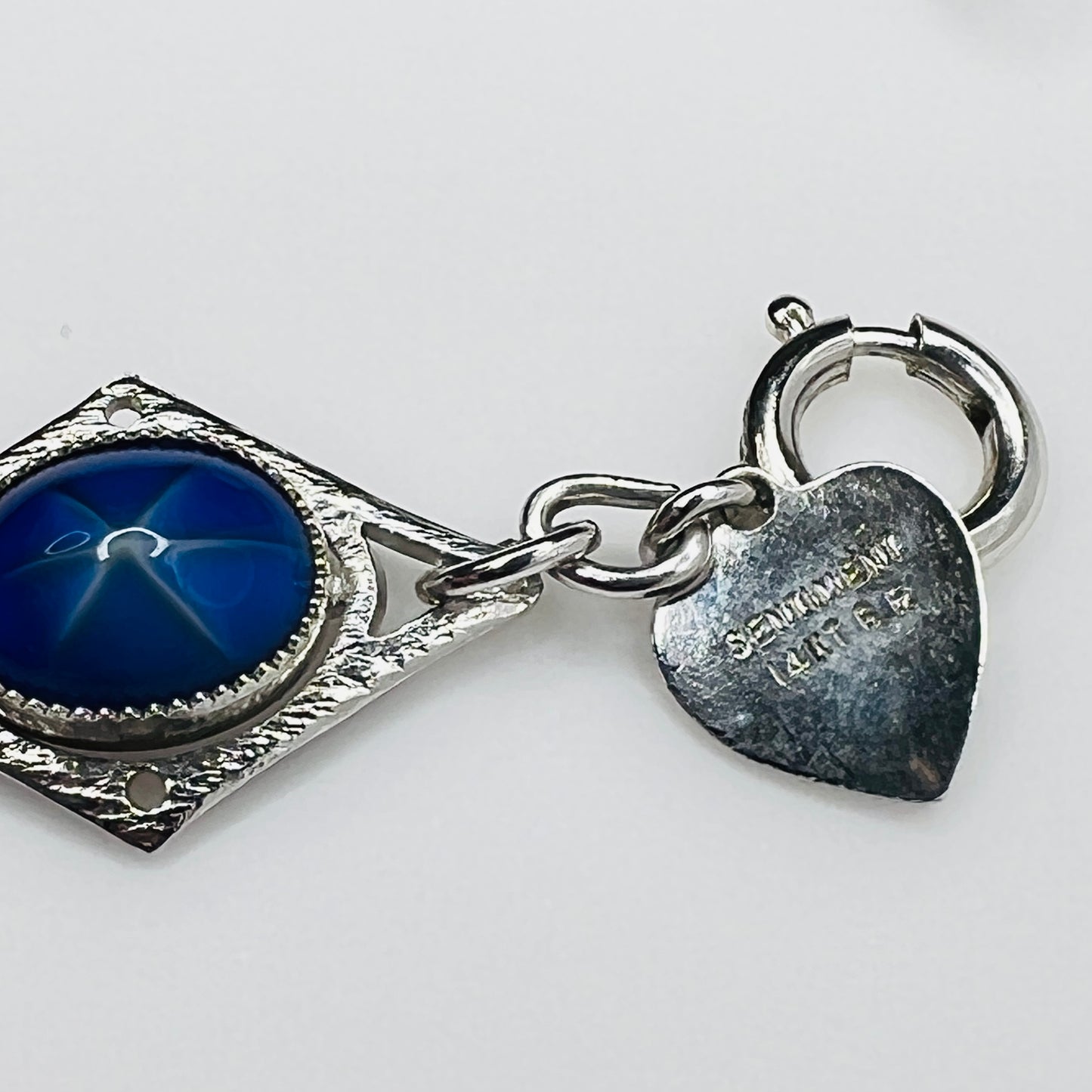 Overhead view of Sentiment bracelet showing blue cabochons, hang tag and clasp