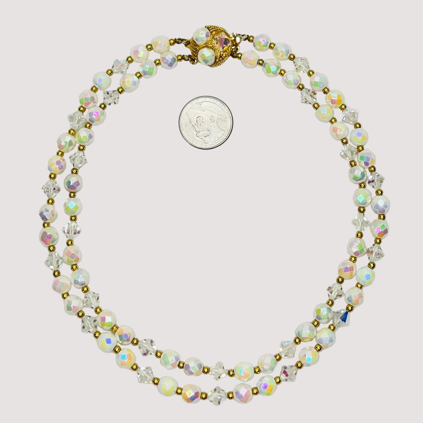 Flat lay of iridescent milk glass and crystal necklace with box clasp