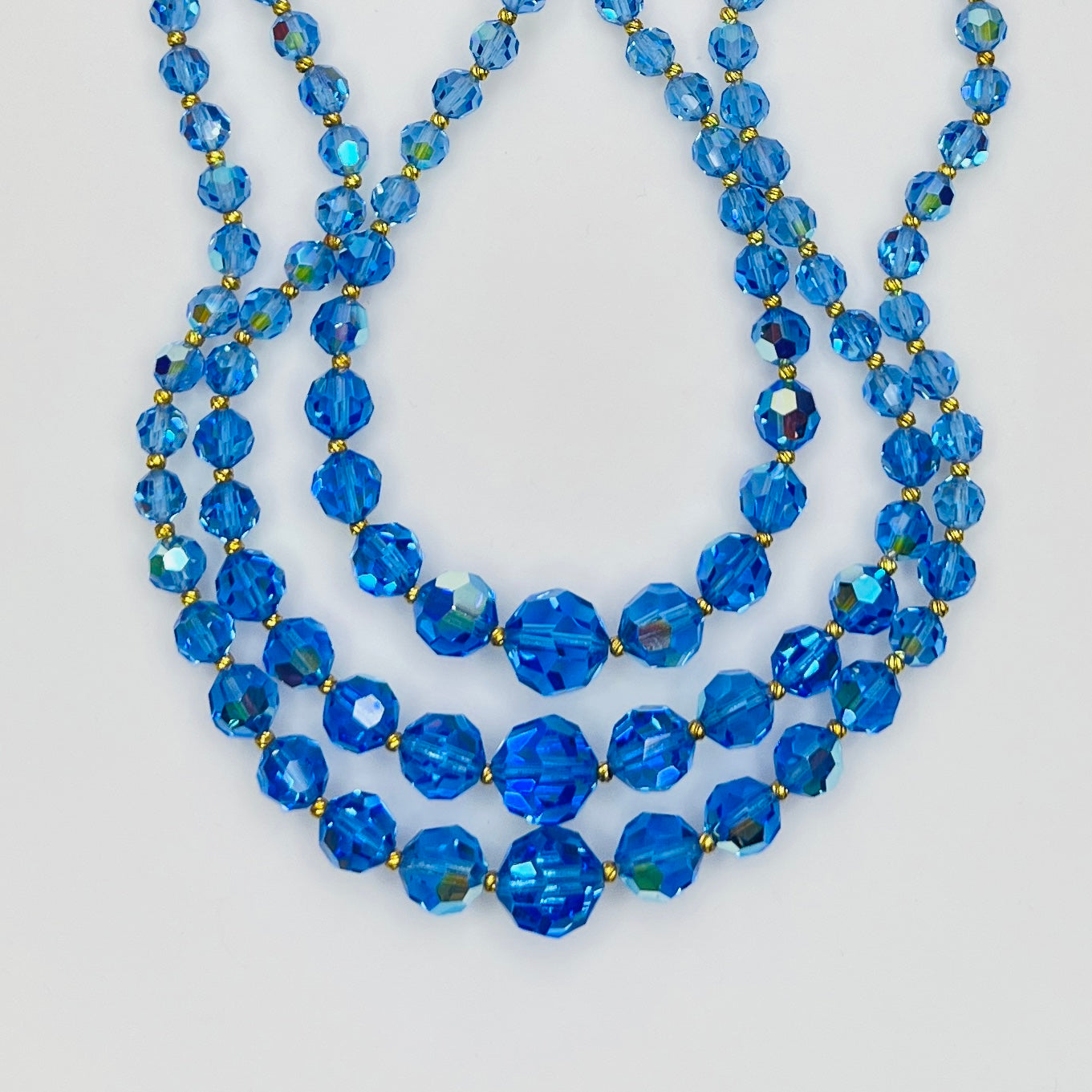 Close-up of graduated blue AB crystal beads with gold-tone spacers