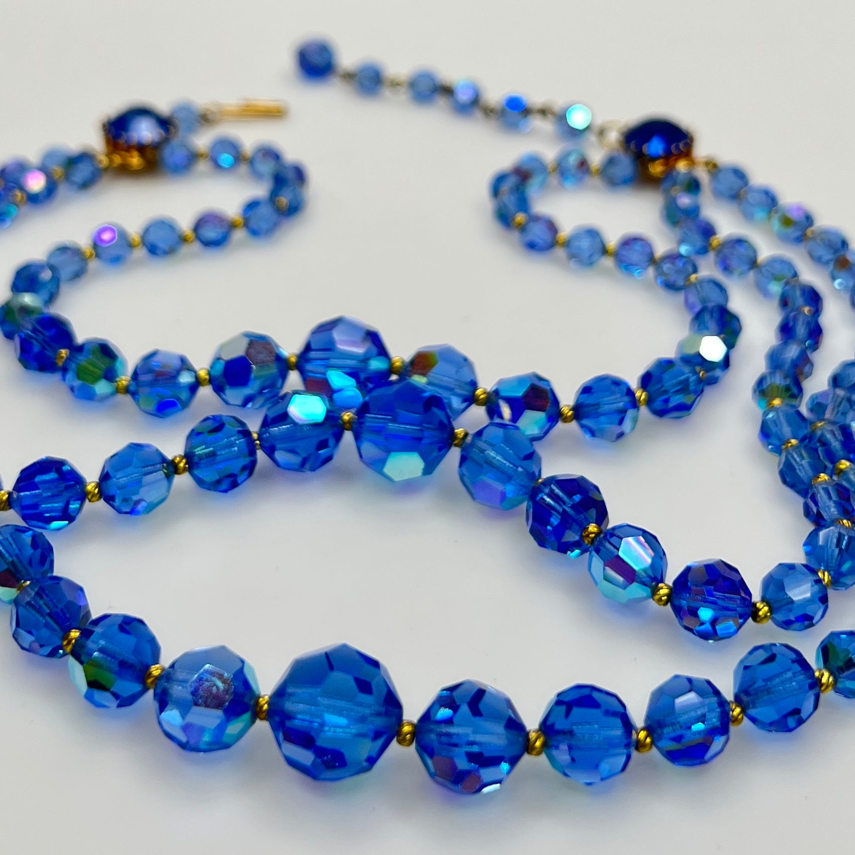 Close-up of graduated blue AB crystal beads with gold-tone spacers