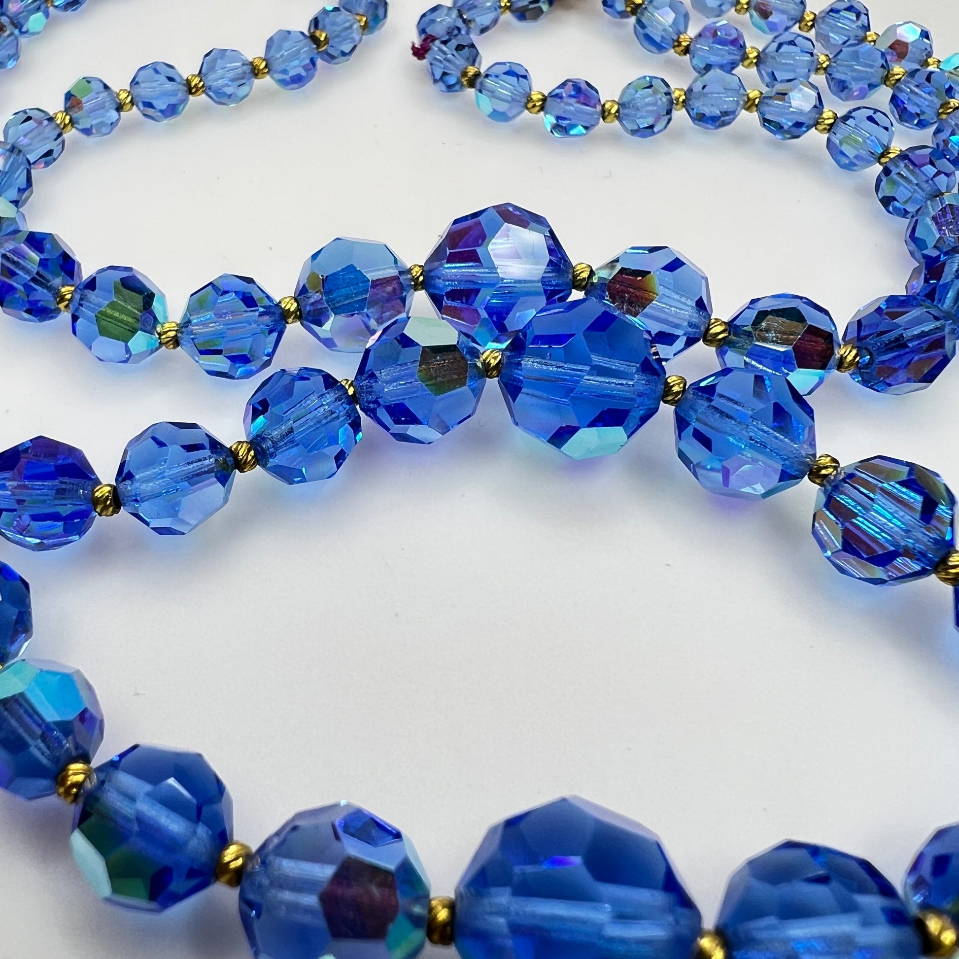 Close-up of graduated blue AB crystal beads with gold-tone spacers