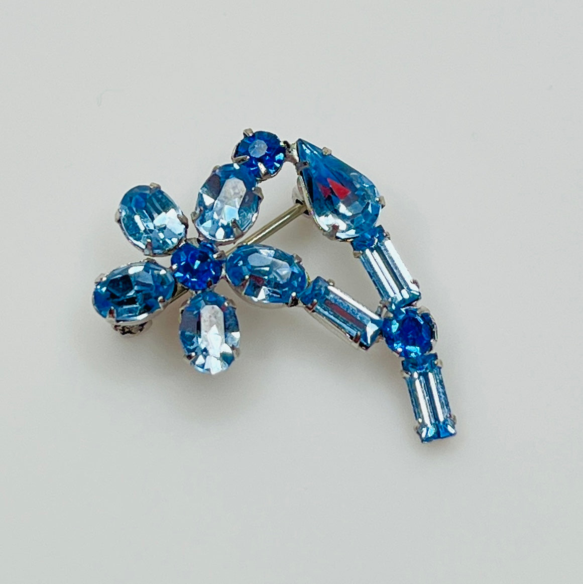 Vintage 1950s blue rhinestone flower brooch in silver-tone setting